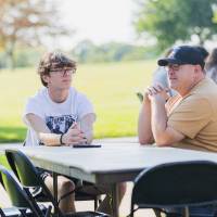 Family talking at table on Kirkhof Lawn.